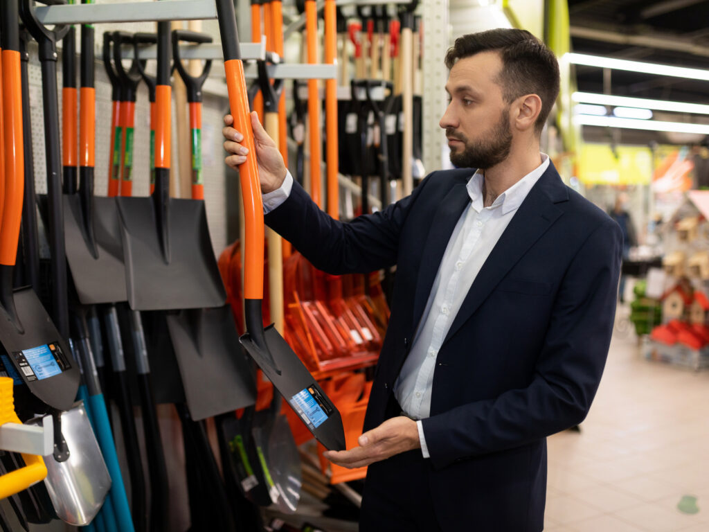 a customer in a garden center purchases a metal shovel for the garden.