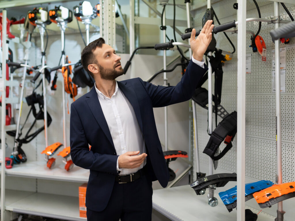 gardening goods store manager offers gas and electric lawn trimmer to choose from.