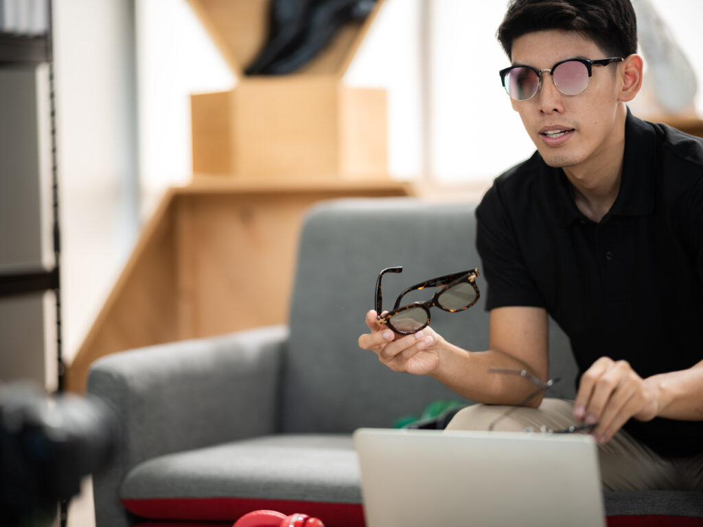 Young male businessman and entrepreneur and social media influencer recording vlog using video camera while talking to audience and going live on social media