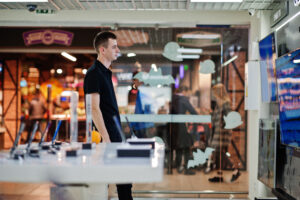 Seller man professional consultant in tech store or shop stand near smart TV.