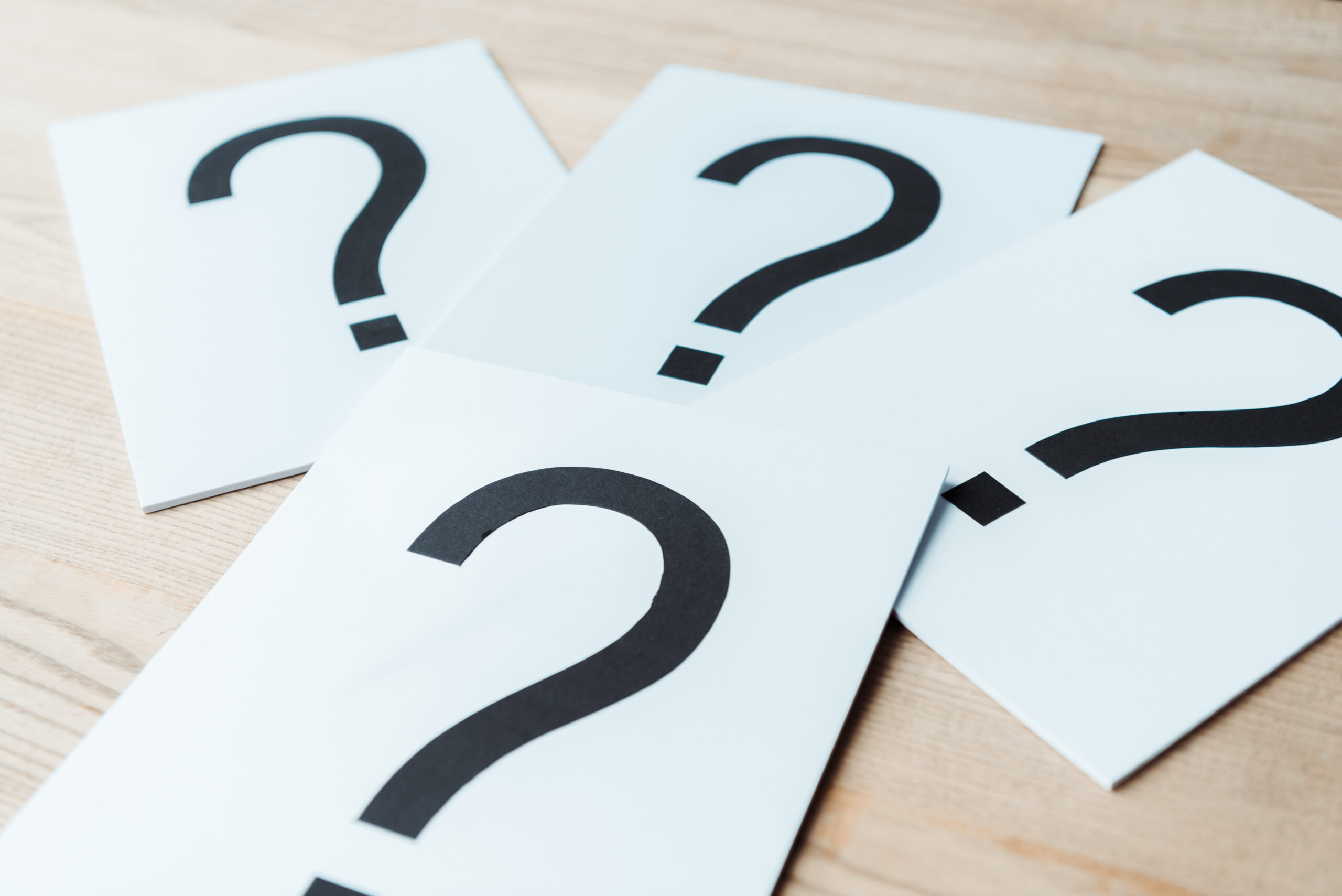 selective focus of black question marks on white papers on wooden table